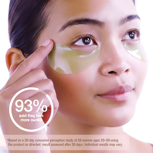 A close-up of a woman applying or wearing pale yellow under-eye gel patches, with a hand touching one patch. A circular badge reads '93% said they look more awake' and there is small disclaimer text at the bottom. *Based on a 30-day consumer perception study of 59 women ages 20-59 using the product as directed; result assessed after 30 days. Individual results may vary. view 2