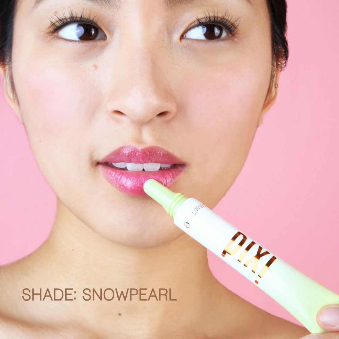 Woman holding a PIXI lip product with a pink background - wearing shade SnowPearl